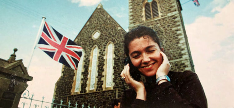Elaine Monaghan talks on a cell phone outside a building that's flying a British flag