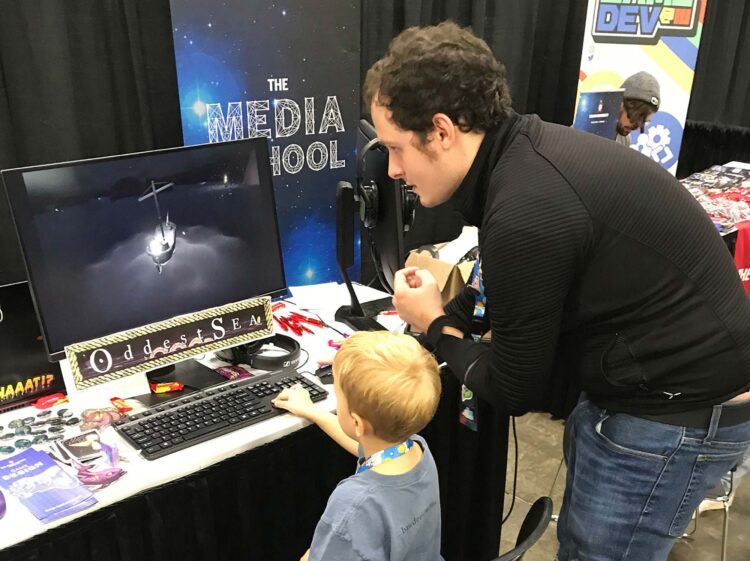 Matt Olry shows a child how to play his video game, 